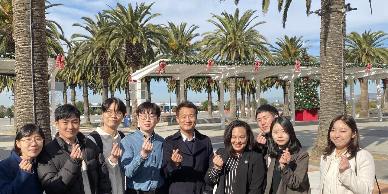 Photograph of smiling adults at an outdoor park with palm trees in the back