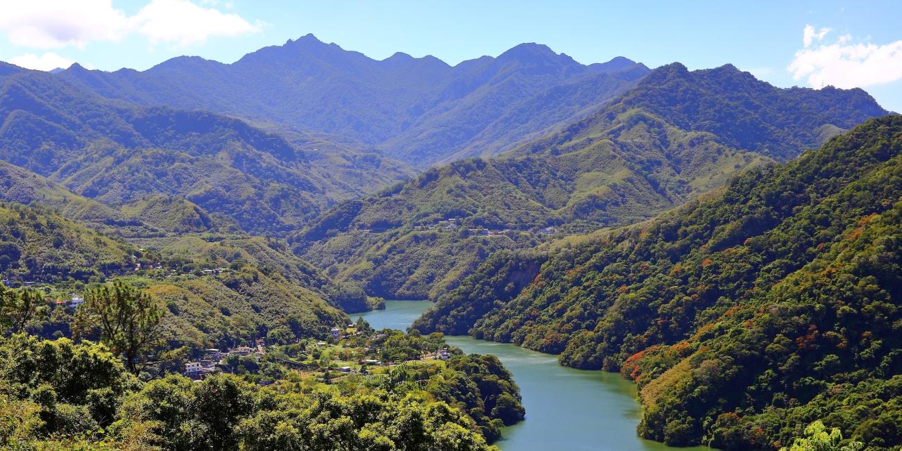 Photograph of lush green hills with river flowing in the middle