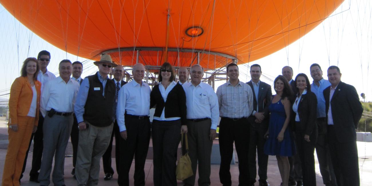 Group of people standing outdoors in front of a large orange balloon.