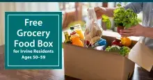 Person's hands filling a cardboard box with fresh groceries on a wooden table.