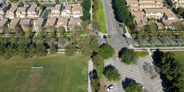 Aerial view of a planned community with houses, roads, a soccer field, and parking.