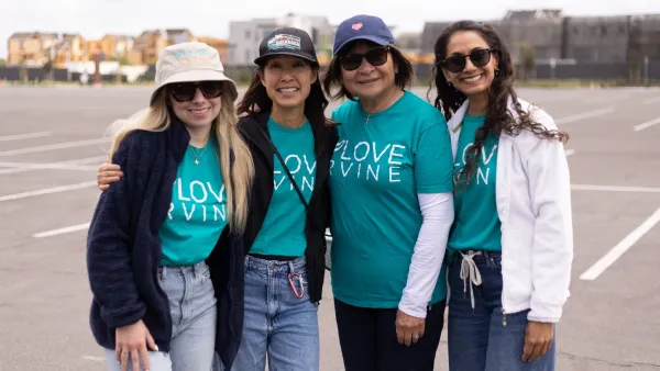 Four smiling women in teal "LOVE IRVINE" shirts stand in a parking lot.
