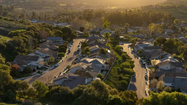Aerial view of a suburban neighborhood nestled in a valley with a golden sunset.