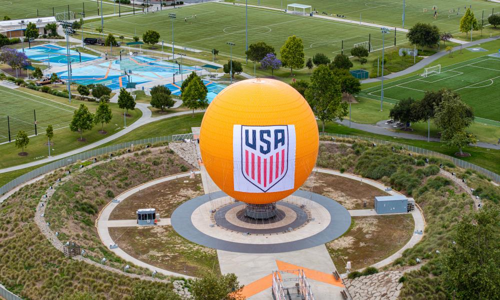 Large orange sphere with USA logo in a circular park, surrounded by green sports fields.