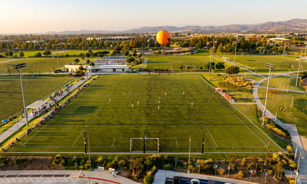 Golden hour aerial view of the Great Park Sports Complex with a soccer game underway and the Great Park Balloon.