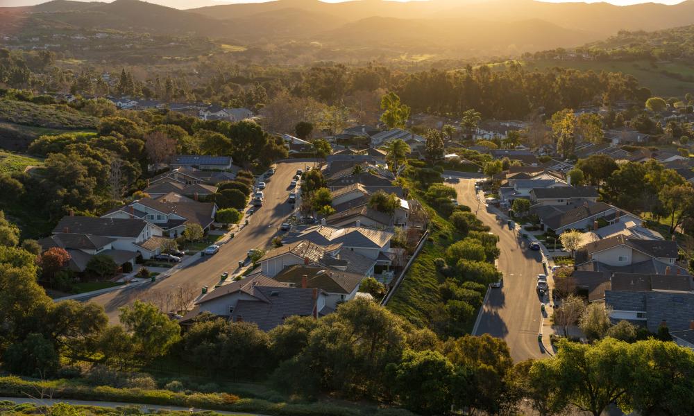 Aerial view of a suburban neighborhood nestled in a valley with a golden sunset.