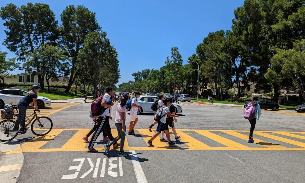 kids walking and bike riding in a crosswalk 