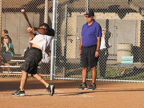 Adult swings bat on baseball field
