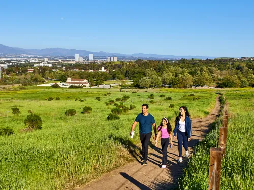 A family of three walking through a trail