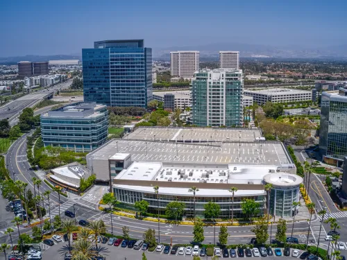 Aerial view of a city with modern office buildings, a large complex, and roads.