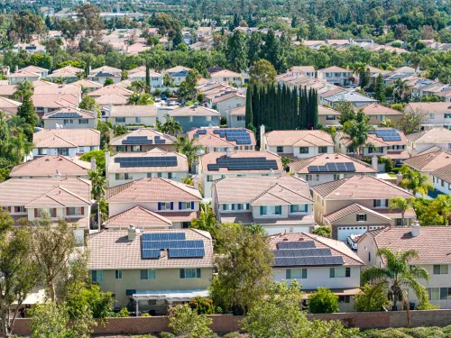 Aerial photo of suburban houses, a wide road, soccer field, and parking lot