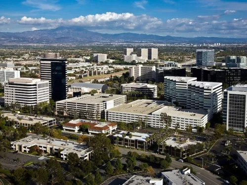 Aerial view of a business park with numerous modern buildings, roads, and distant mountains.